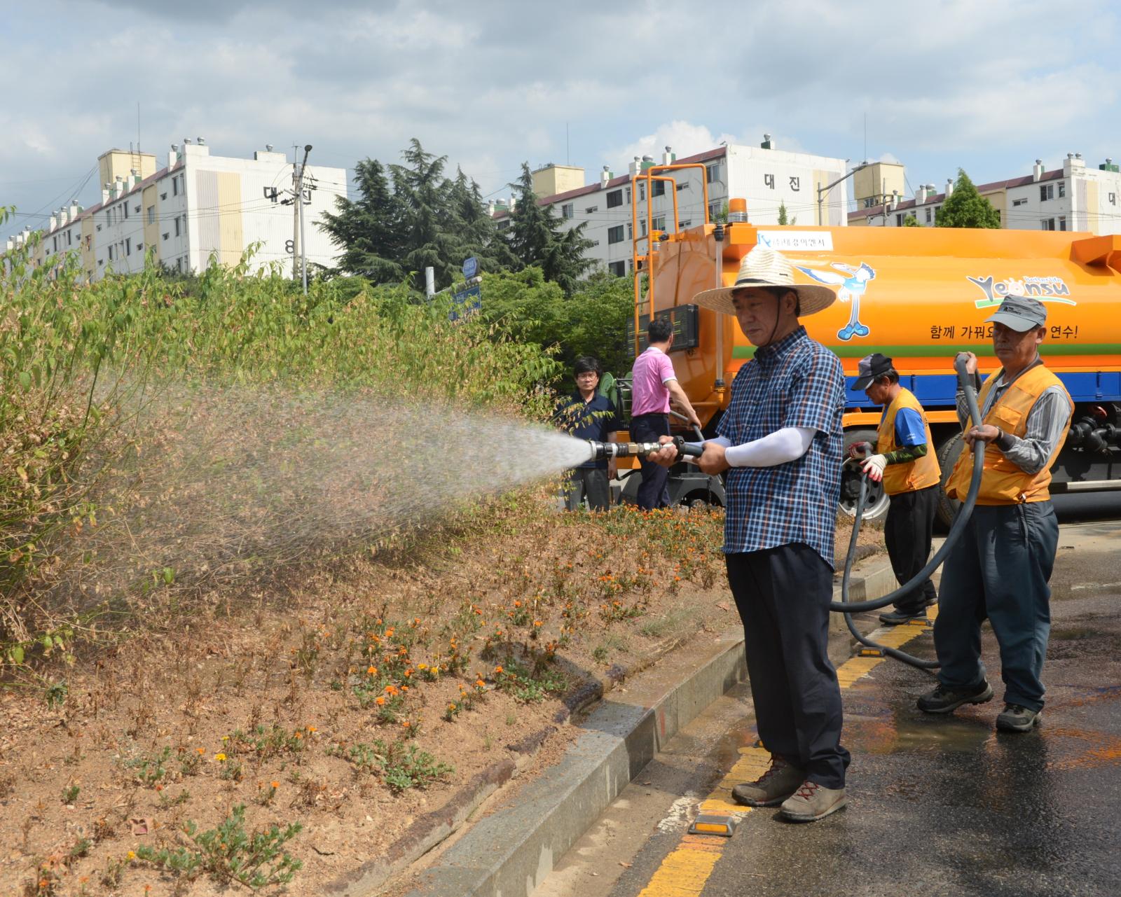 선학사거리 화단에 물주기 행사에 참석하여 호수를 들고 물을 주고 있는 고남석 연수구청장