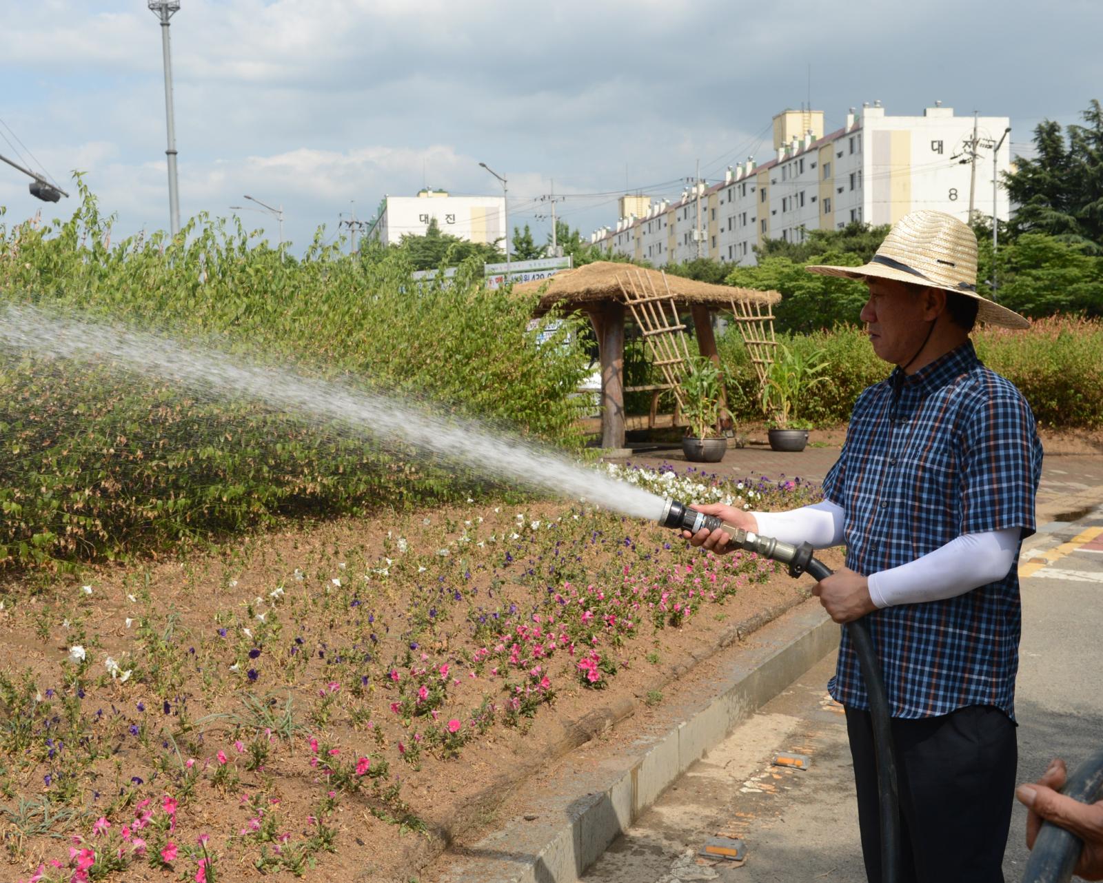 선학사거리 화단에 물주기 행사에 참석하여 호수를 들고 물을 주고 있는 고남석 연수구청장